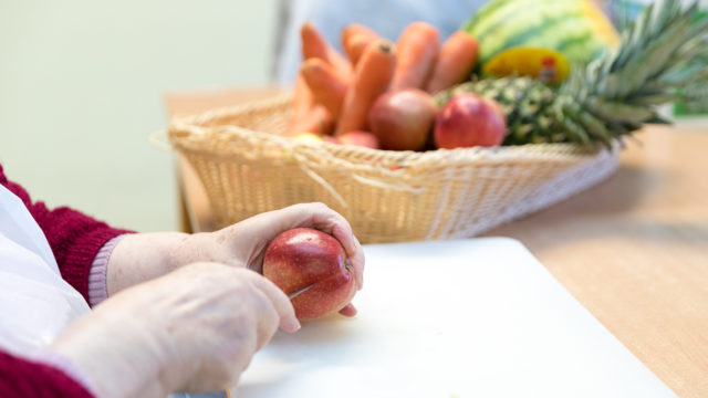 Eine Frau schneidet eine Apfel auf dem Obstkorb im Pflegeheim Seniorenresidenz Uelzen