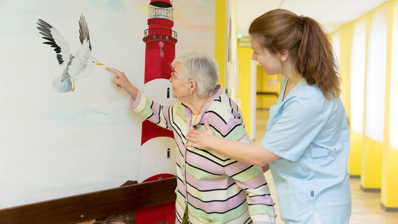 Eine ältere Frau freut mich mit einer Pflegerin über ein Bild im Altenheim Seniorenresidenz Uelzen